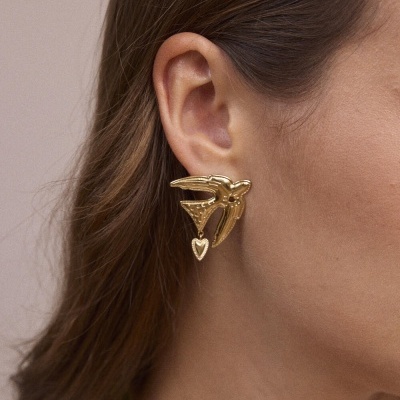 Brinco dourado em forma de pássaro com coração pendurado no ouvido de mulher