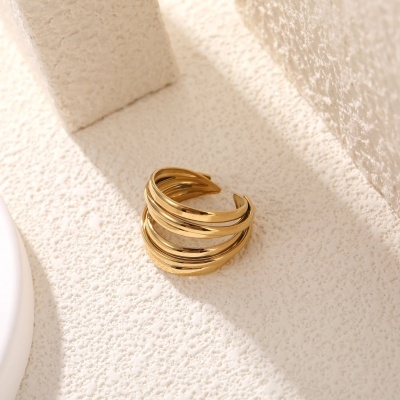 Anel aberto dourado em superfície branca texturizada
