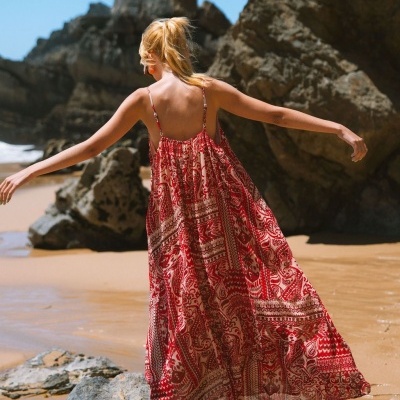 Vestido longo fluído vermelho e branco com padrão floral e geométrico na praia