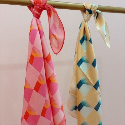 Dois lenços coloridos pendurados em varão metálico.