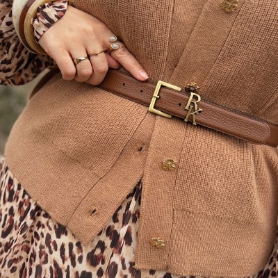 Mãos com anéis, pulseiras, cardigan castanho e camisa com padrão leopardo.