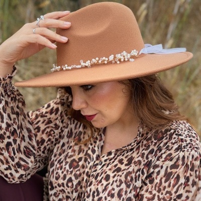 Chapéu castanho claro com decoração de pérolas e cristais em mulher com blusa animal print.