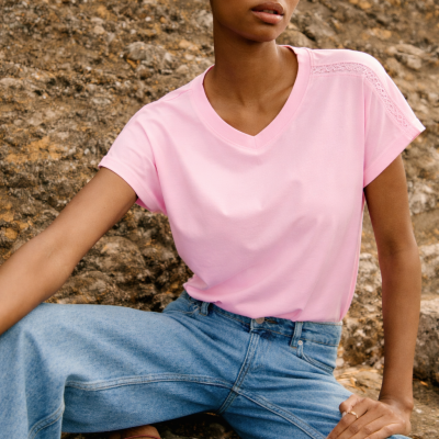Mulher com t-shirt rosa e jeans azuis sentada em rocha