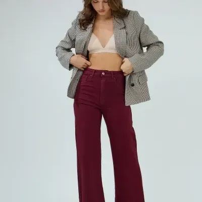 Mulher com blazer pied-de-poule preto e branco e calças vinho em fundo branco