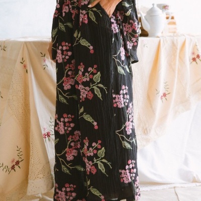 calças pretas largas com padrão floral rosa e verde, bolso lateral, sapatos baixos castanhos