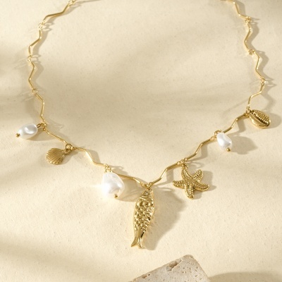 Colar dourado com pendentes marinhos e pérolas sobre fundo claro