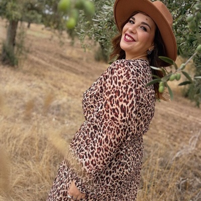 Vestido animal print castanho usado por mulher com chapéu castanho em campo seco com oliveiras