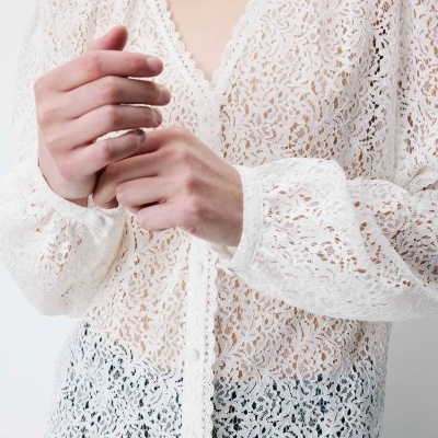 Blusa branca de renda com padrão floral e decote em V