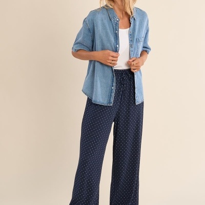 Mulher com camisa de ganga azul e calças largas azuis com pontos brancos