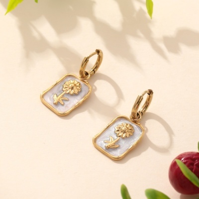 Brincos de argola dourados com pendente de flor em relevo branco perolado