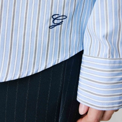 Camisa azul às riscas com bordado e mãos ao lado