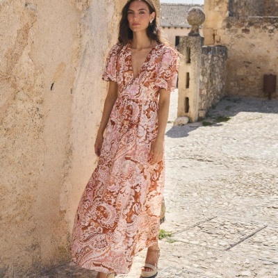 Vestido longo com padrão floral rosa e castanho em ambiente exterior de pedra