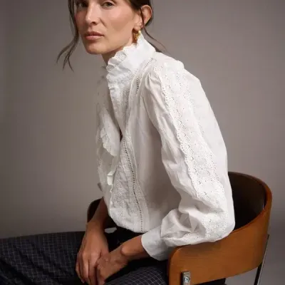 Blusa branca feminina com detalhes em renda e bordados nas mangas e gola alta