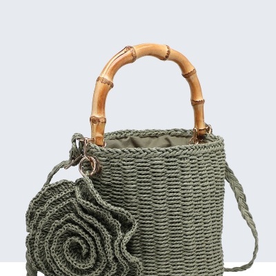 Mala verde trançada com alça de bambu e adorno floral