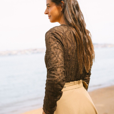 Blusa castanha de renda e saia bege numa praia