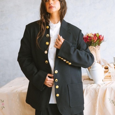 Casaco preto com botões dourados e camisa branca com gola franzida