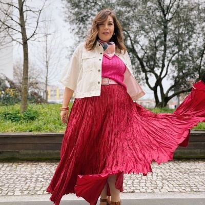 Mulher com roupa colorida em ambiente exterior com árvores e relva