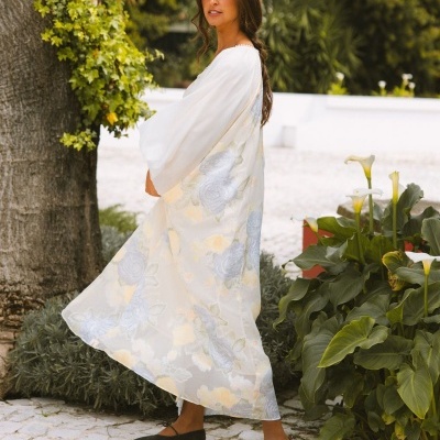 Vestido longo branco com padrão floral e mangas largas usado por mulher ao ar livre