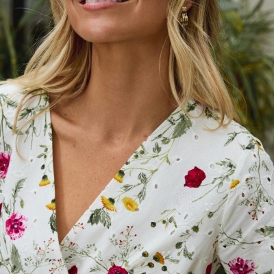 Blusa branca com flores vermelhas e amarelas e recortes circulares