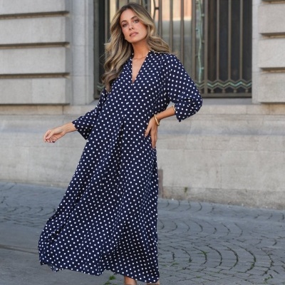 Vestido comprido azul com bolinhas brancas na rua ao lado de edifício de pedra
