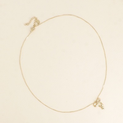 Colar fino dourado com pendente em forma de laço.