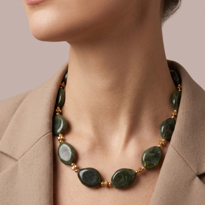Colar verde marmoreado com contas douradas usado com blazer bege.