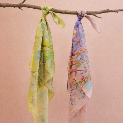 Dois lenços florais pendurados num galho contra fundo rosa