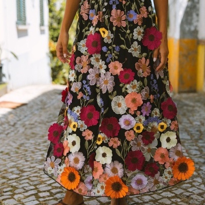 Saia preta longa bordada com flores coloridas e sandálias castanhas.