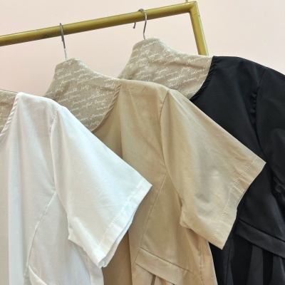 Três vestidos lisos branco, bege e preto pendurados em cabides com texto