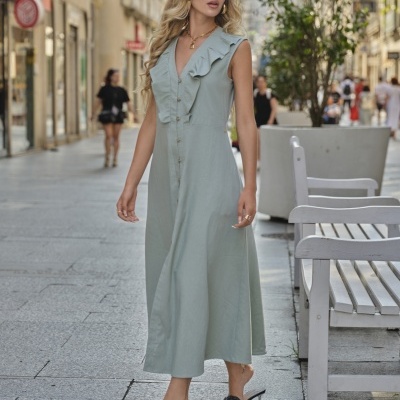 Vestido comprido verde-água com babado no decote usado por mulher numa rua urbana