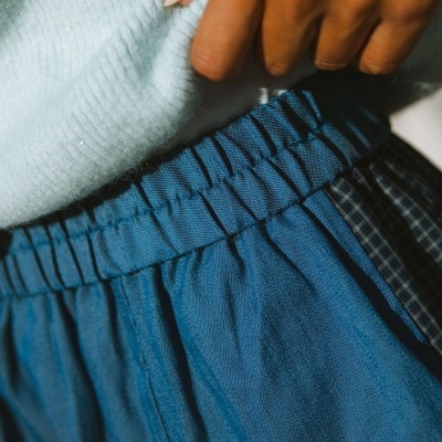Roupa azul com elástico na cintura e malha castanha clara com mão feminina