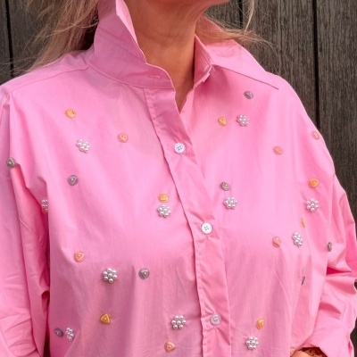 Camisa rosa bordada com flores e triângulos coloridos