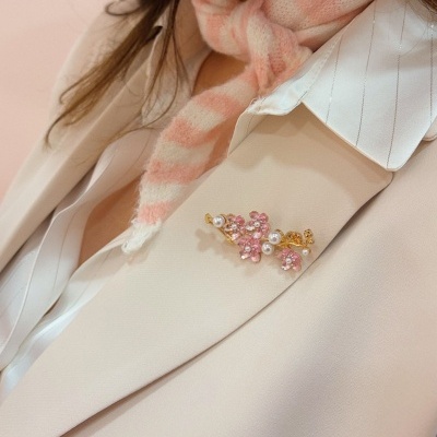 Broche flores rosa e pérolas num blazer bege claro com camisa branca e lenço rosa