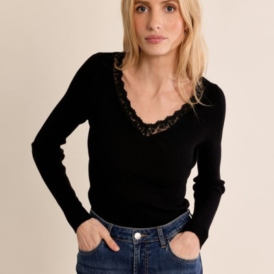 Mulher com camisola preta de malha com renda e jeans azuis de cintura alta.