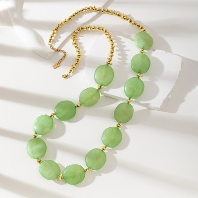 Colar com contas verdes ovais e pequenas douradas, fecho ajustável, sobre fundo branco.