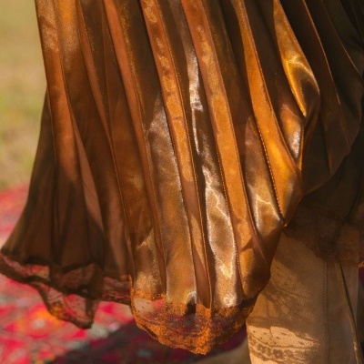 Saia plissada castanha dourada com borda rendada e bota castanha clara.