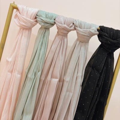 Lenços de várias cores com pequenas pérolas pendurados num cabide amarelo