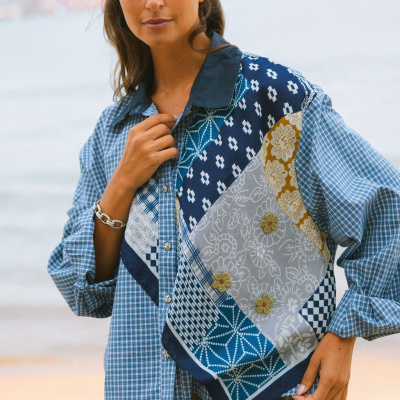Bela blusa feminina de tecido misto com padrão patchwork azul e amarelo, com vários padrões e botões, usada na praia.