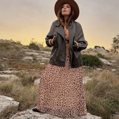 Vestido longo animal print, casaco de pele castanho e chapéu castanho em cenário natural