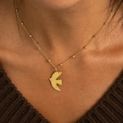 Colar dourado com pendente em forma de pássaro