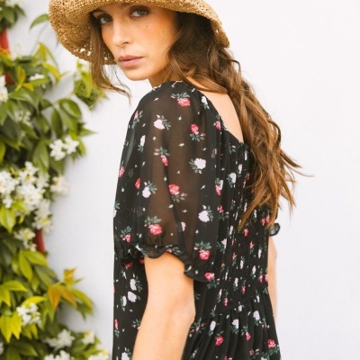 Vestido feminino preto com padrão floral e mangas bufantes ao ar livre com chapéu de palha