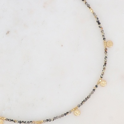 Colar de contas cinza e douradas com medalhas penduradas sobre fundo branco