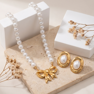 Conjunto de colar e brincos com pérolas e detalhes dourados sobre base de pedra clara
