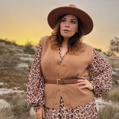 Mulher com vestido de padrão leopardo, colete e chapéu castanhos