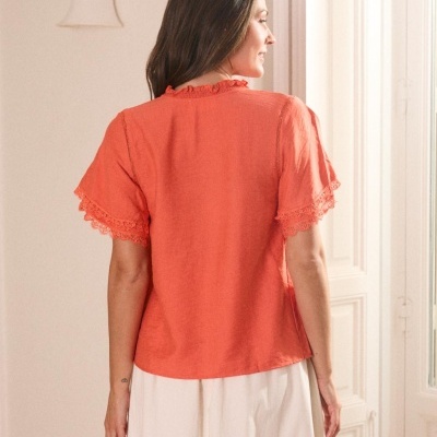 T-shirt laranja feminina com renda nas mangas vista de costas