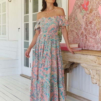 Mulher com vestido comprido floral em ambiente interior com decoração clara