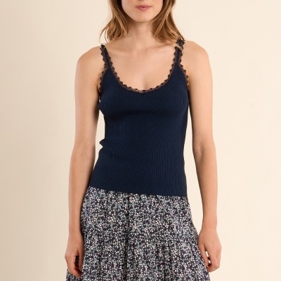 Mulher com top azul escuro de alças e saia floral comprida