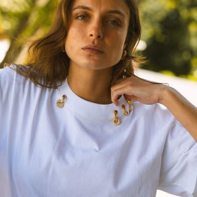 T-shirt branca com detalhes dourados na gola usada por mulher