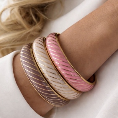 Pulseiras douradas com padrão colorido em diagonal no pulso