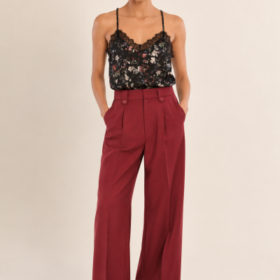 mulher vestindo top preto floral com alças finas e calças largas vermelhas vinho com cintura subida